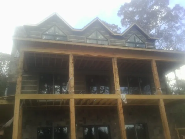 Dormers and porch framing on a large log home under construction — Roof Coating work by our crew in Pine Valley