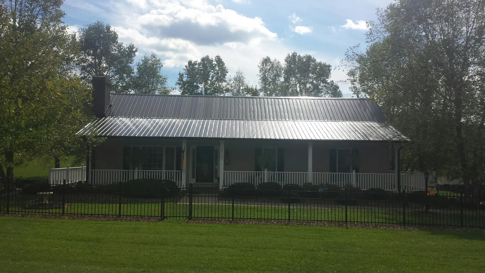 Gray metal roof on a brick ranch with a full width front porch — Gutter Guard Installation work by our crew in Pine Valley
