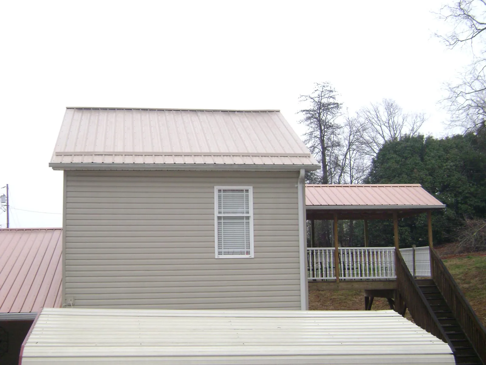 Tan metal roofs on a two story addition and attached porch, from a Roof Replacement job in Pine Valley