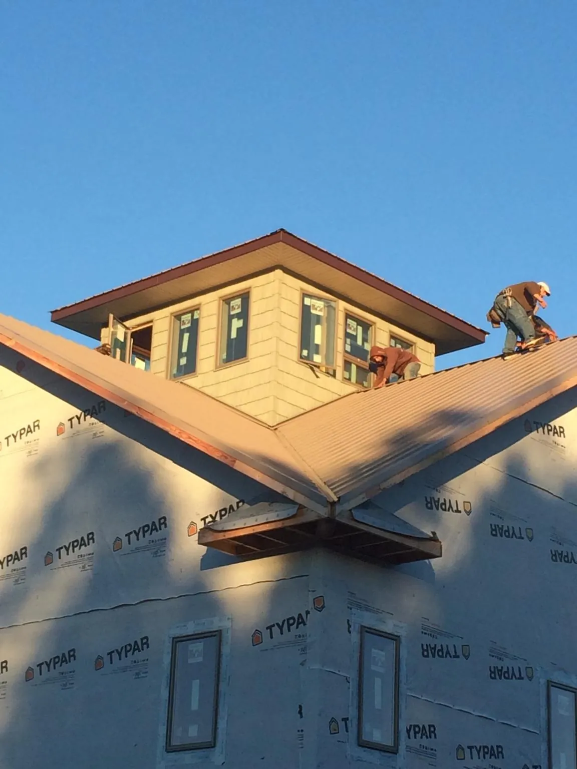 Roofers working around a rooftop cupola on a new metal roof at sunset — Roof Waterproofing in Pine Valley by Roofing Brothers
